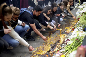 Люди залишають квіти і свічки у пам’ять про загиблих біля будівлі сербської школи, де сталася стрілянина 3 травня, за день до нової трагедії