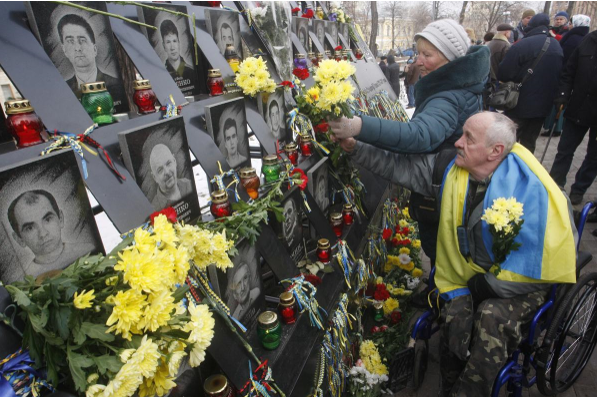 Українці приносять квіти до пам’ятника вбитим активістам Майдану. Фото: pa/dpa/Сергій Гловний