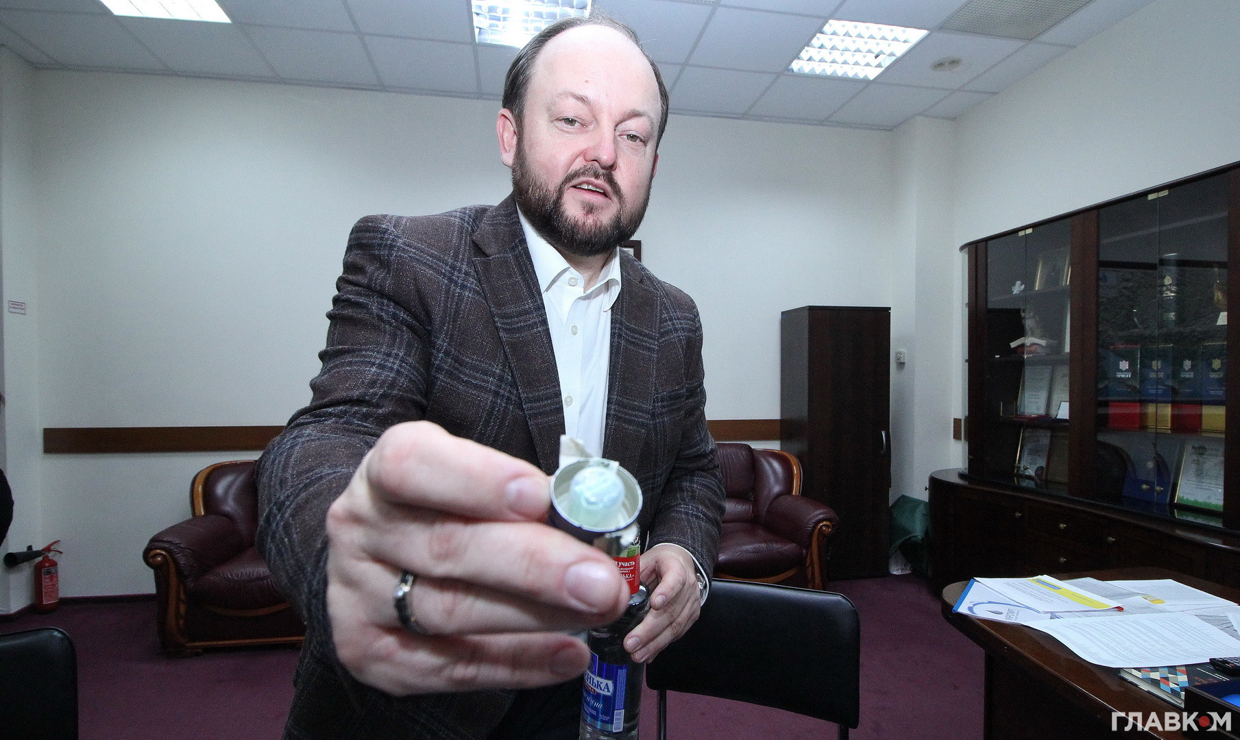 Керівник «Укрспирту» Сергій Блескун демонструє, на які йдуть виробники горілки. Під кришку від склянки з горілкою вкладено 20-гривневу купюру