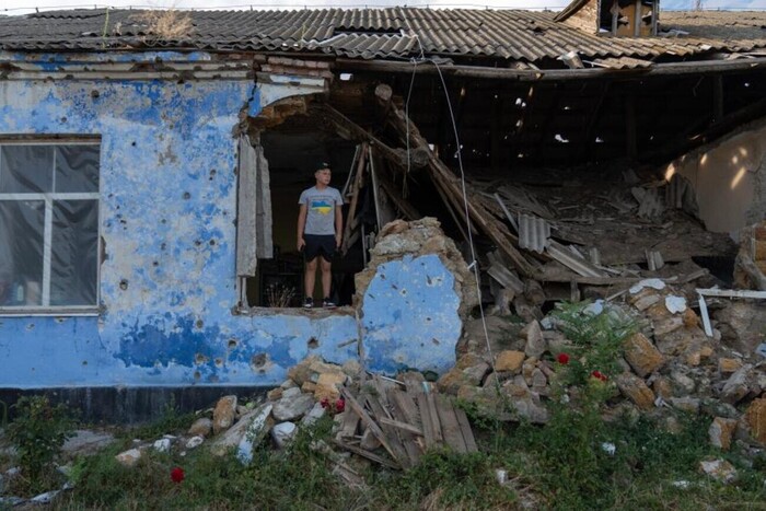 15-летний Саша стоит возле своей разрушенной школы в селе Новогригоровка на юге Украины, 22 июля 2023 года 
