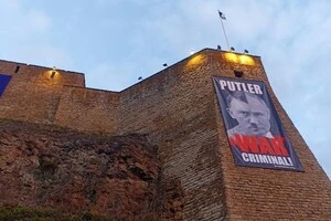 На плакаті, розміщеному на стіні Нарвського замку, написано: «Путлер – воєнний злочинець»