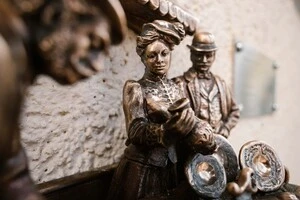 На скульптурі зображений прилавок, за яким торгує подружжя і підписує угоду про постачання з клієнтом