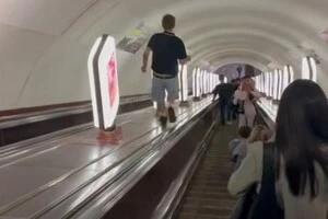Хлопець біг по балюстраді між ескалаторами станції метро «Хрещатик», чіпляючись рукою за рекламні світильники
