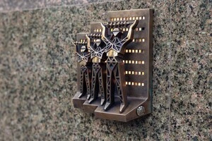 Якщо натиснути на кнопку збоку мініскульптури, вікна в мініатюрних будинках за постатями бронзових енергетиків засяють