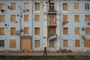 26 листопада у Краматорську чоловік іде поряд із пошкодженою будівлею