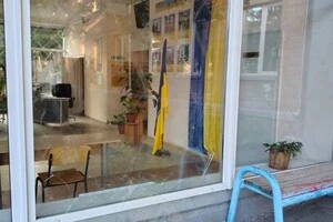 Потрощені вікна в одному зі столичних ліцеїв, крізь які видно прапор України