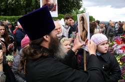 Священнослужитель московської церкви кріпить «георгіївську стрічку» на портрет