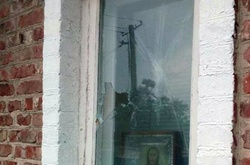 Пошкоджене осколками вікно будинку