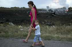  Жінка з дитиною проходить повз одне з місць падіння уламків «Боїнга», збитого російською установкою «Бук», у результаті чого загинуло 298 людей, у тому числі 80 дітей. Донеччина, неподалік села Грабове, 17 липня 2014 року</sp
