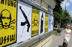 Люди проходять біля плакатів у столиці Польщі в розпал збройної агресії Росії проти України. Варшава, 14 липня 2014 року