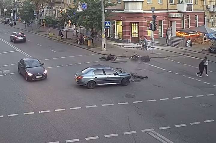 Байкер із мотоциклом відлетіли на тротуар: у Києві сталося серйозне ДТП (відео)