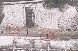 Два комунальники косять траву під снігом