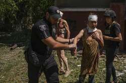  Поліцейський надає допомогу постраждалій жінці після обстрілу росіянами житлового кварталу в Краматорську, 7 липня 2022 