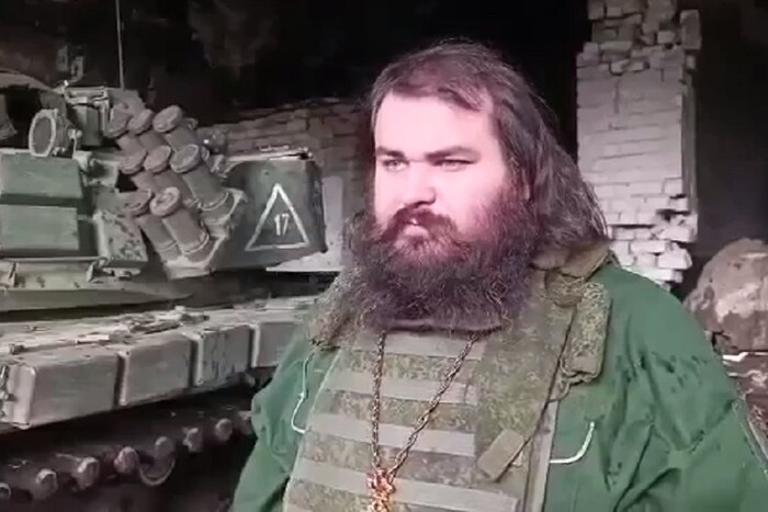 Російський батюшка у бронежилеті освячує ржаві танки (відео)