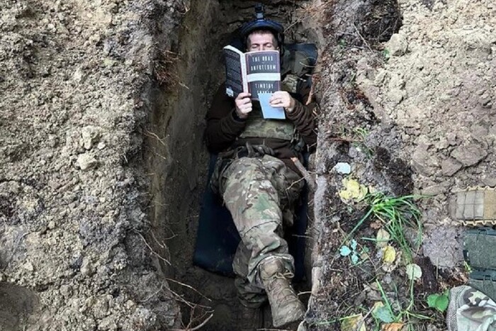 Українців вразило фото військового, який читає в окопі 