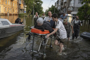 Волонтери тягнуть жінку на ношах під час евакуації 