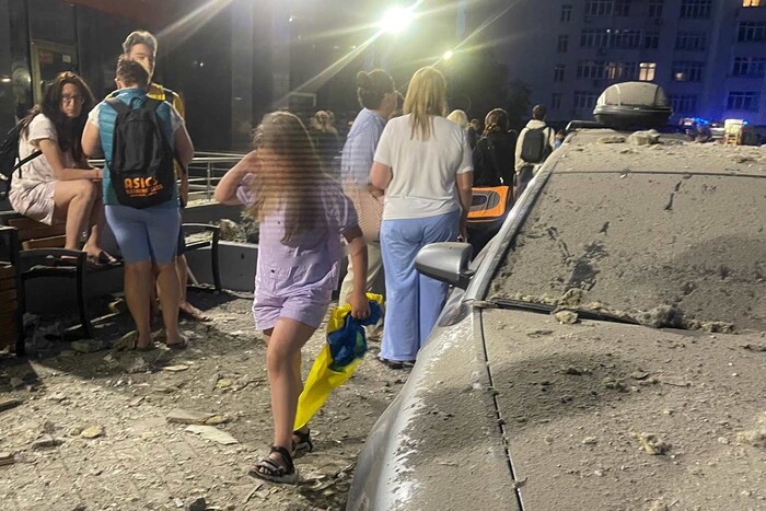 Фото дня. Дівчинка вибігає зі зруйнованої багатоповерхівки у Києві з прапором