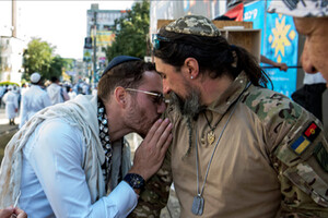 Хасид-прочанин цілує шеврон у вигляді червоно-чорного прапора з зіркою Давида на руці українського військового