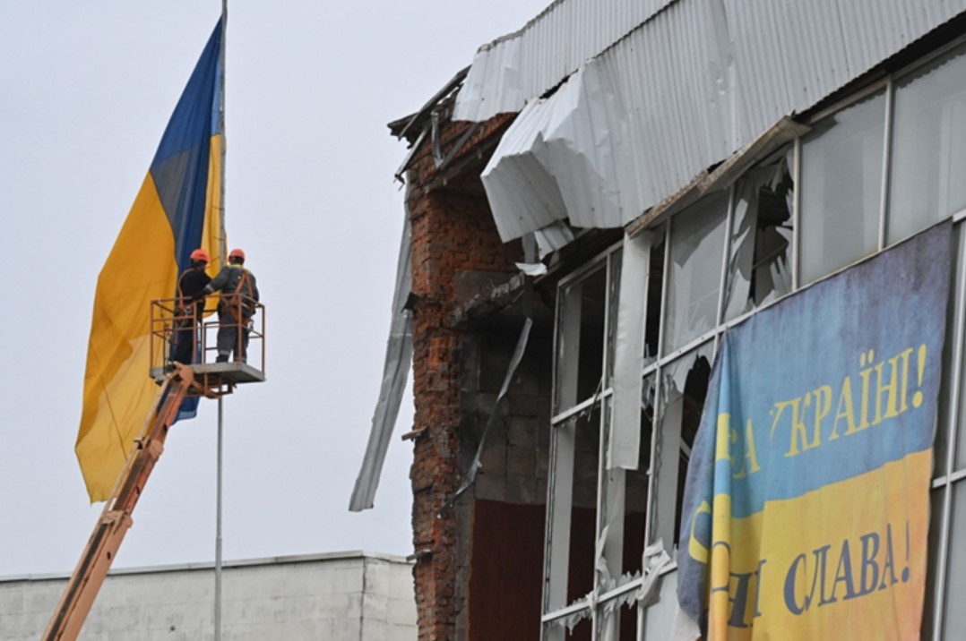 Робітники піднімають український прапор на флагшток біля зруйнованого будинку у центрі Макарова. 10 квітня, 2022 року