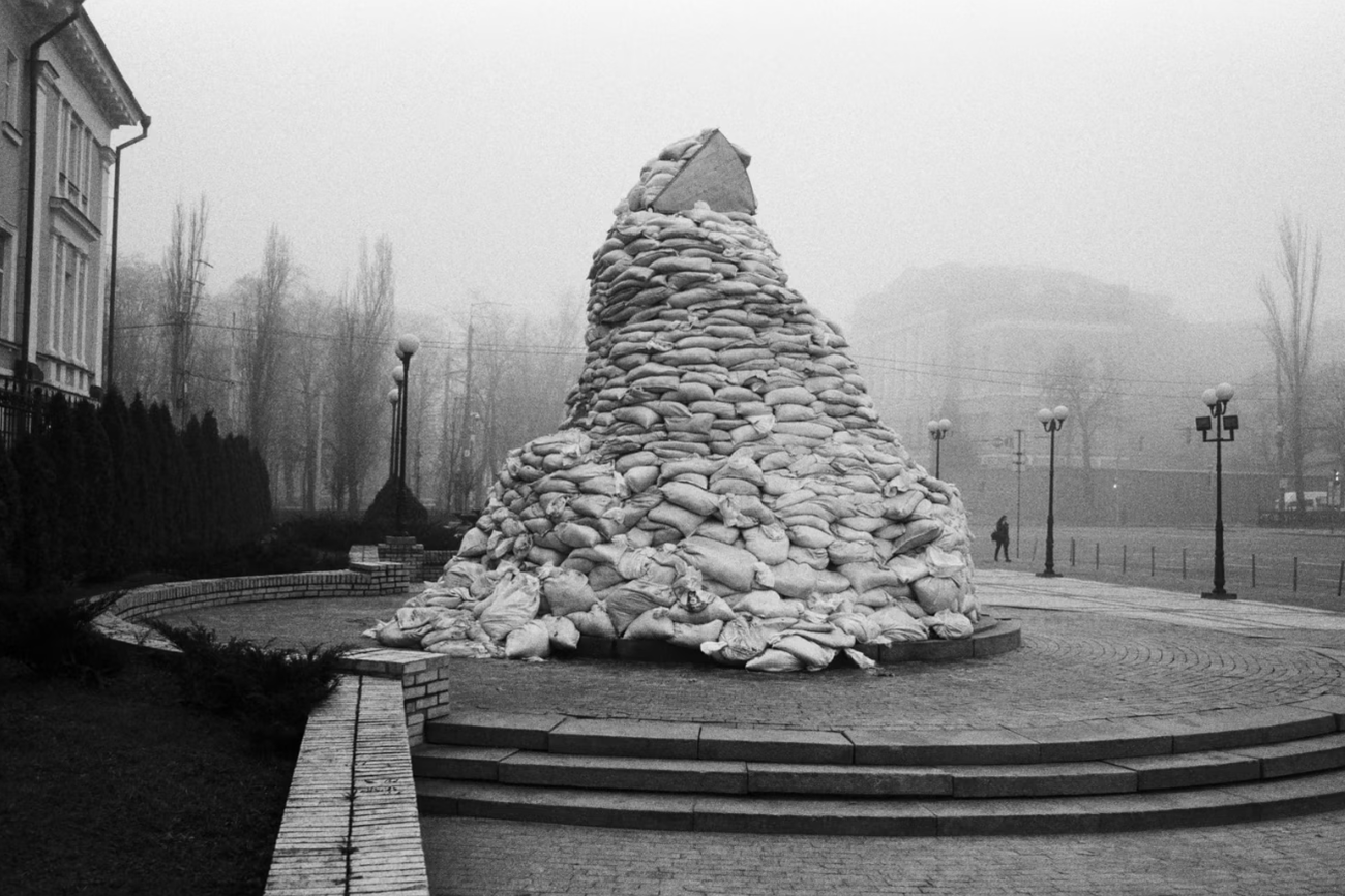 Березень 2022 року. Центр Києва, пам’ятник Грушевському хочуть убезпечити від прильотів, обклавши мішками з піском