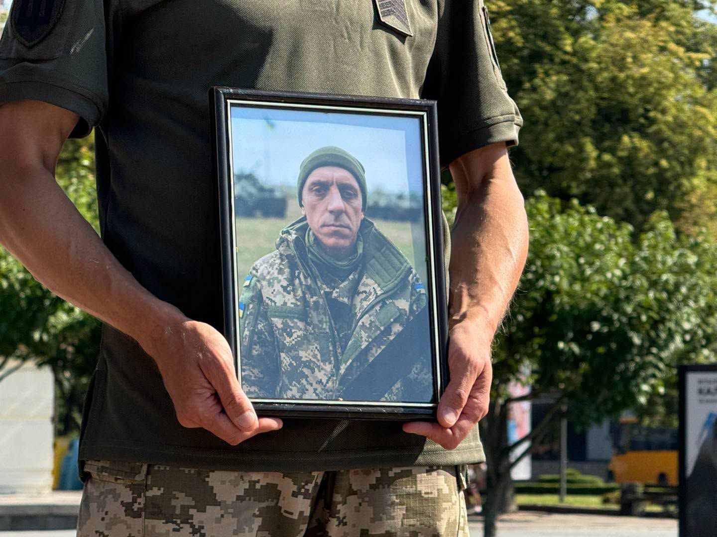 Військовий тримає траурний портрет захисника