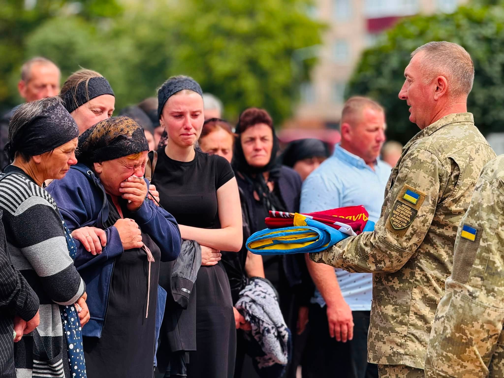 Військовий передає прапор України родині полеглого захисника