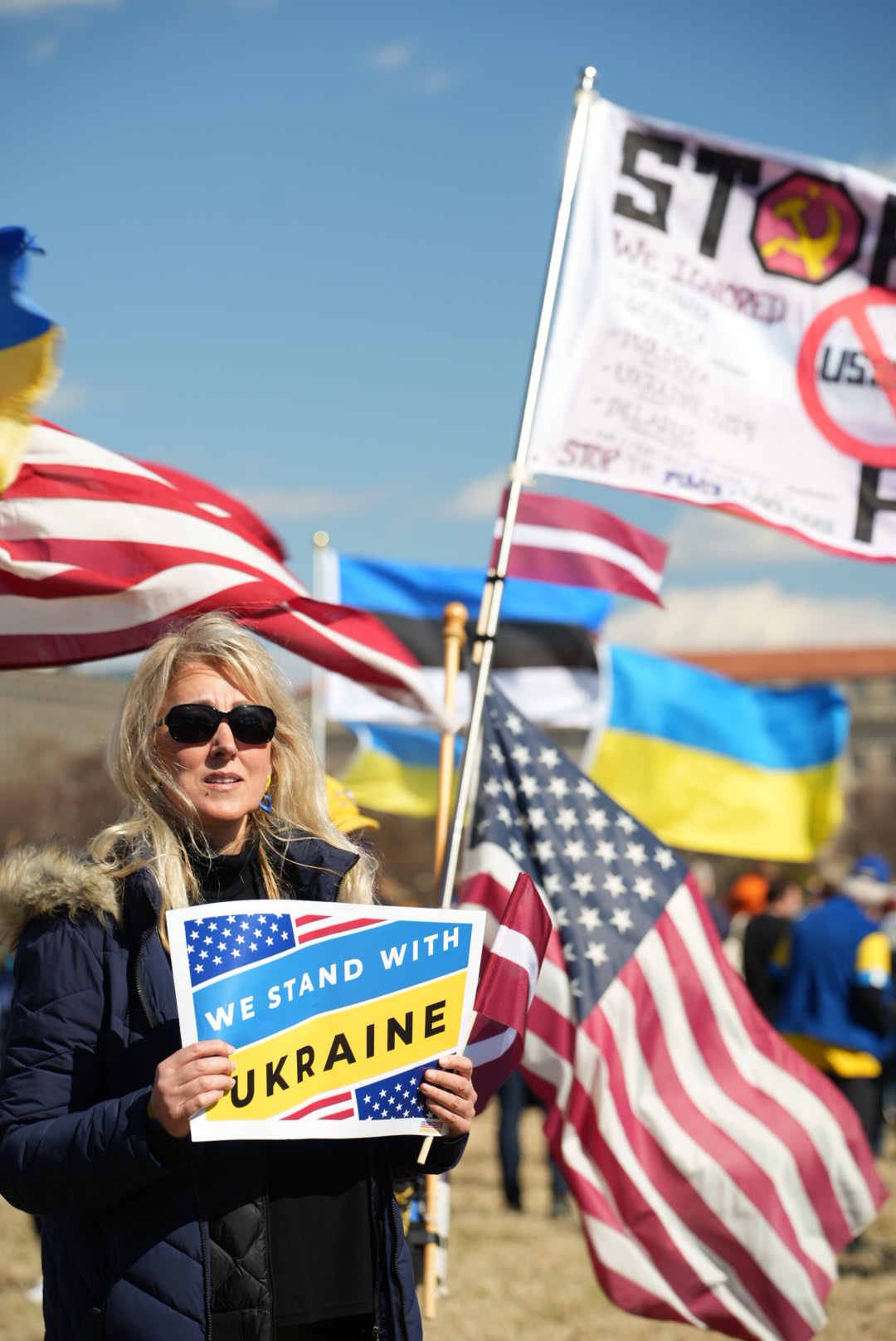 Учасниця акції тримає табличку з написом «We stand with Ukraine»