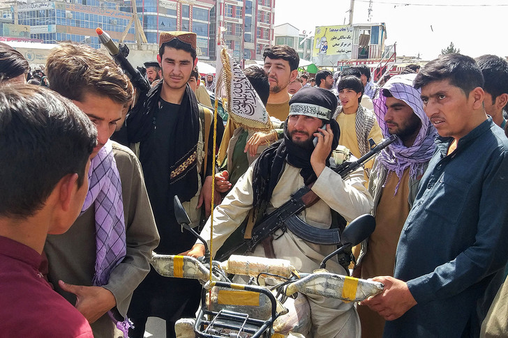 Боец Талибана в окружении местных жителей в Пули-Хумри 11 августа 2021 года.