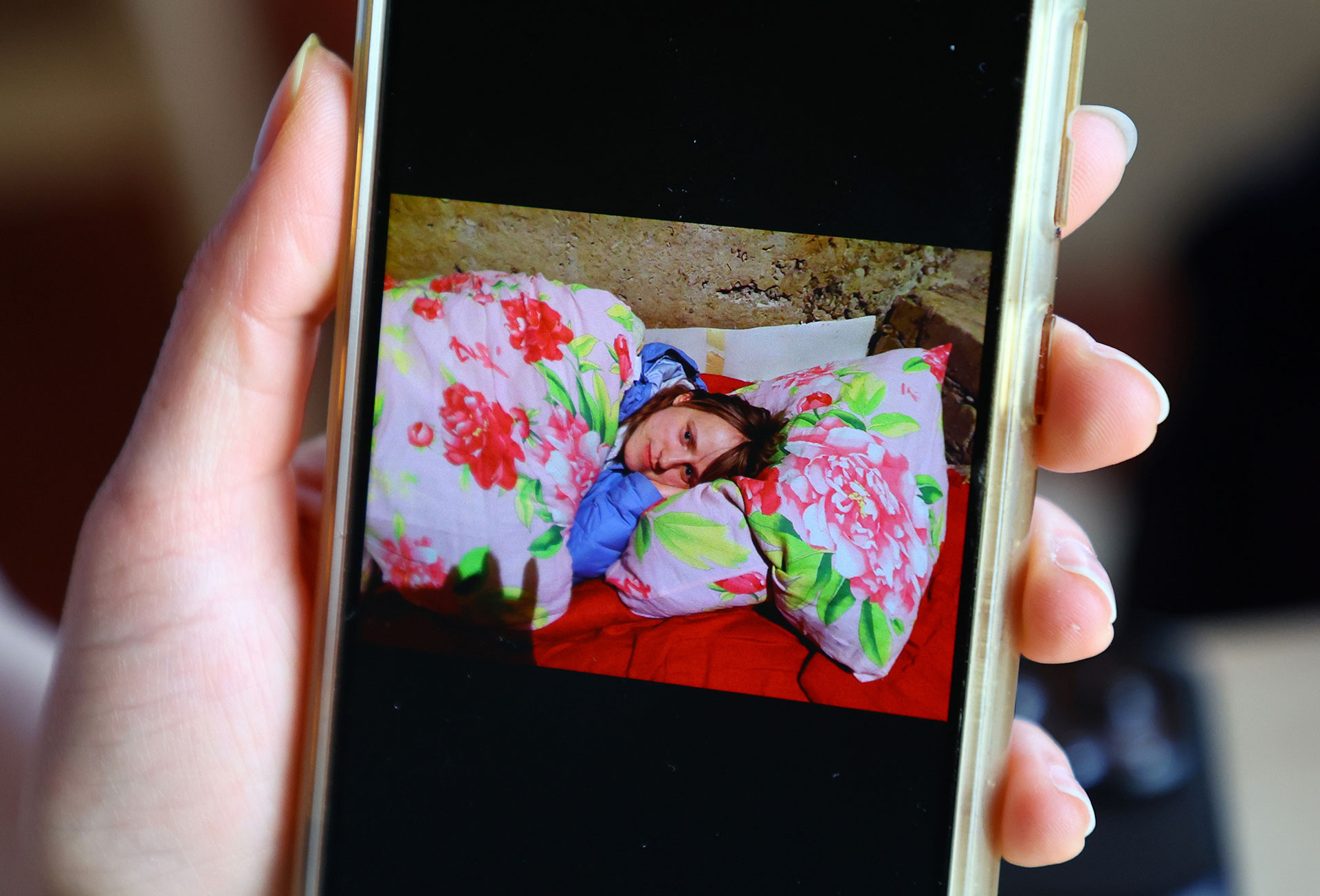 Вікторія Науменко показує на своєму телефоні фото з підвалу, де ховалася під час обстрілів (фото: reuters)