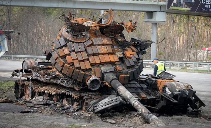 Комунальщик роздивляється знищений російський танк на дорозі у напрямку столиці України (Фото: АР)