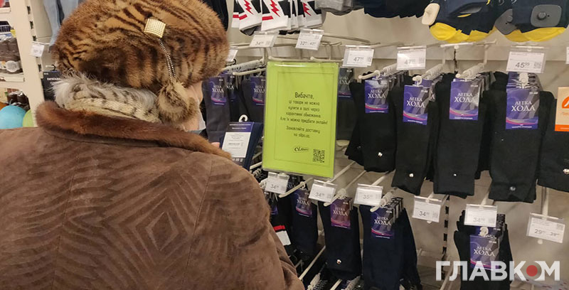 Жінка у супермаркеті в місті Хмельницький придивляється до шкарпеток під час січневого локдауну