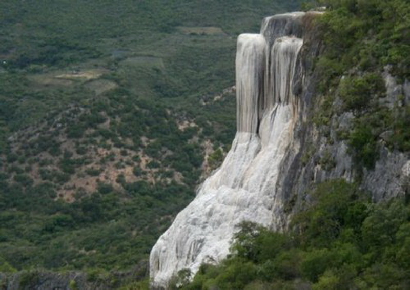 Иерве-эль-Агуа (Hierve el Agua), Оахаса (Oaxaca). Это место может выглядеть, как водопад, однако на самом деле оно является естественным скальным образованием.   Иерве-эль-Агуа (что в переводе с испанского означает "вода кипит") формировался на протяжении веков: минеральная вода, насыщенная карбонатом кальция, стекала с его вершины, образуя сталактиты и с течением времени формируя вот такой потрясающий каменный водопад.  На самом деле здесь два каменных водопада — Большой (высотой 30 метров) и Малый (высотой 12 метров). Наиболее посещаемый — Малый водопад, так как до него добраться гораздо легче. Кроме того, на самом верху находится естественный бассейн с минеральной водой, полезной для здоровья, поэтому туристы не упускают случая искупаться в нём, наслаждаясь открывающейся с него потрясающей панорамой каньона.
